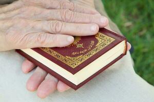 The Koran in the hand of senior woman photo