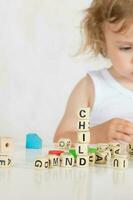 Small girl composes words from letters. Closeup photo