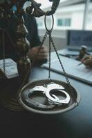 Justice and law concept.Male judge in a courtroom with the gavel, working with, computer and docking keyboard, eyeglasses, on table in morning light photo