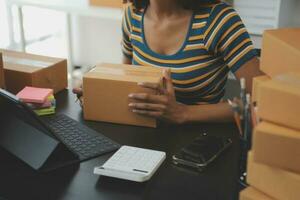 Business woman start up small business entrepreneur SME success .freelance woman working at home with Online Parcel delivery. SME and packaging deliveryconcept photo