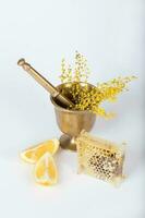 Mimosa flowers in a bronze mortar on a gray plastic surface. photo