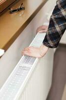 Old woman keeps her hands at the heater photo