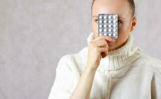 Young caucasian lady  dressed in a knitted sweater with medication. Closeup photo