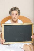 Old woman between 70 and 80 years old with a black chalkboard photo