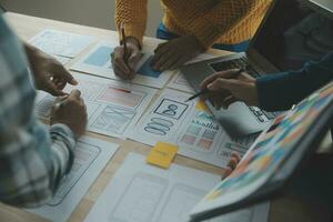 Close up ux developer and ui designer brainstorming about mobile app interface wireframe design on table with customer breif and color code at modern office.Creative digital development agency photo