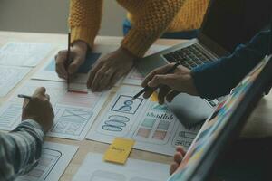 Close up ux developer and ui designer brainstorming about mobile app interface wireframe design on table with customer breif and color code at modern office.Creative digital development agency photo