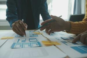Close up ux developer and ui designer brainstorming about mobile app interface wireframe design on table with customer breif and color code at modern office.Creative digital development agency photo