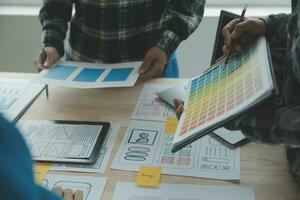 Close up ux developer and ui designer brainstorming about mobile app interface wireframe design on table with customer breif and color code at modern office.Creative digital development agency photo