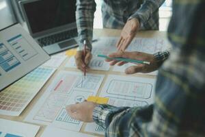 Close up ux developer and ui designer brainstorming about mobile app interface wireframe design on table with customer breif and color code at modern office.Creative digital development agency photo