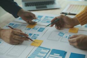 Close up ux developer and ui designer brainstorming about mobile app interface wireframe design on table with customer breif and color code at modern office.Creative digital development agency photo