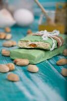 Almond turron covered by pistachio chocolate on a wooden surface. photo