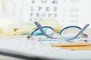 Eyeglasses for children on a eye chart close to eye pads. photo