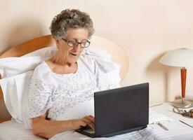 Old woman is communicating through her computer wit hrelatives photo