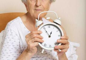 Old woman with vintage alarm clock photo