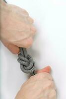 Rope with a simple knot on a white surface. Closeup. photo