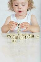 Small girl composes words from letters. Closeup photo