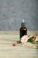 Rose hip syrup in a dark glass dropper bottle on a wooden surface. photo