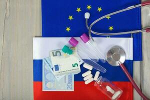 Medication,test tubes,money and stethoscope on European and Russian flags photo