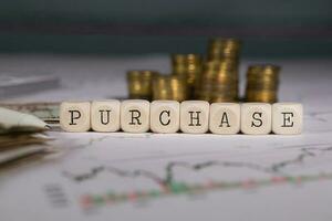 Word PURCHASE composed of wooden letters. Stacks of coins in the background. photo