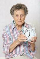 Old woman with vintage alarm clock photo