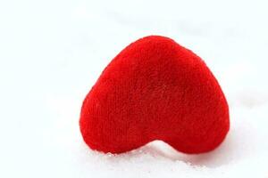 Red plush heart in the snow. photo