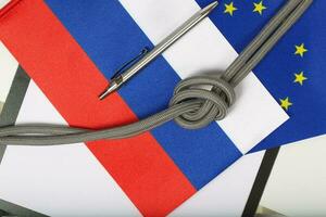Two flags of EU and Russia,rope with a knot and a pen. Background photo