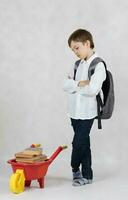 Schoolboy pushes plastic wheelbarrow full of books. Free space for a text. photo