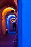 Bologna,Italy- June 23, 2023-People stroll at night under the arcades leading to the sanctuary of San Luca illuminated for the first edition of the Bologna arcades Festival. photo