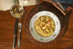 hermosa plato de camarón risotto con blanco vino. en el antecedentes antiguo libros foto