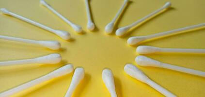 Heap of cotton swabs, cotton buds or cotton stick  on yellow background. Hygienic cosmetic and healthcare accessory. photo