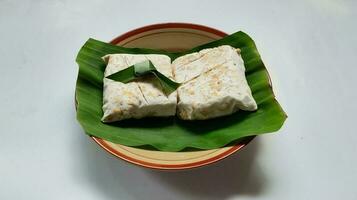 crudo tempeh, tempeh o tempe en plátano hojas, indonesio tradicional alimento, hecho desde fermentado soja cerca arriba. foto