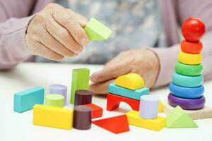 Asian elderly woman playing puzzles game to practice brain training for dementia prevention, Alzheimer disease. photo