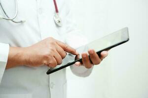 Asian woman doctor holding mobile phone or tablet for search method of treatment patient in hospital. photo