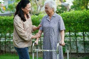 Caregiver help Asian elderly woman disability patient sitting on wheelchair in park, medical concept. photo