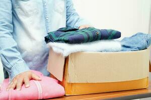 Clothes donations in cardboard box for volunteer. photo