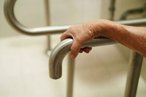 Asian elderly old woman patient use toilet support rail in bathroom, handrail safety grab bar, security in nursing hospital. photo