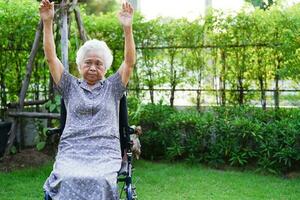 Asian elderly woman disability patient exercise on wheelchair with doctor in park, medical concept. photo