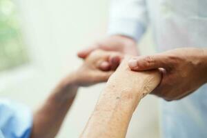 Doctor holding hands Asian elderly woman patient, help and care in hospital. photo