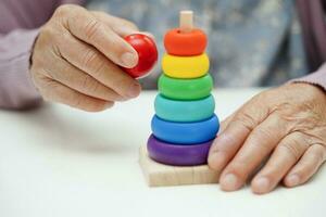 Asian elderly woman playing puzzles game to practice brain training for dementia prevention, Alzheimer disease. photo