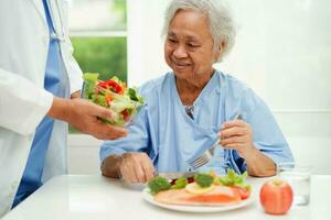 Asian Nutritionist holding healthy food for patient in hospital, nutrition and vitamin. photo