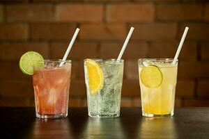 Glass of lime caipirinha drink on top of table in front of a brick wall with text space photo