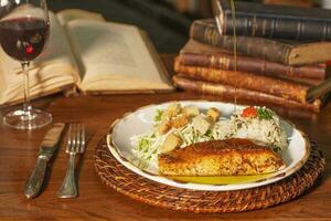 Beautiful plate of grilled fish with rice. In the background old books photo