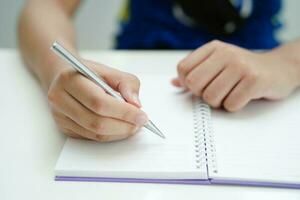 asiático Adolescente estudiante escribir tarea, estudiar lección para examen en línea aprendizaje educación. foto