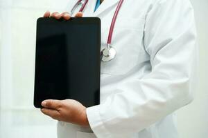 Asian woman doctor holding mobile phone or tablet for search method of treatment patient in hospital. photo