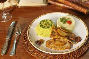 Beautiful pork dish with farofa and puree. In the background old books photo