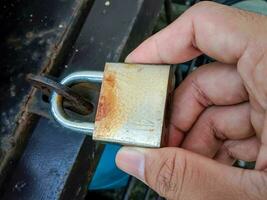 A man's hand holding an old, rusty padlock photo