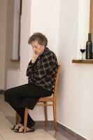 Old woman of 80 years old stays close to the window photo