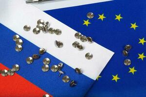 Two flags of EU and Russia covered by pins. Background photo