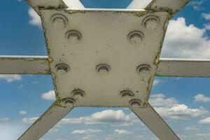 Bolts and nuts on metal plates of steel structure of heavy duty straight crossbar of frame and bridge support photo