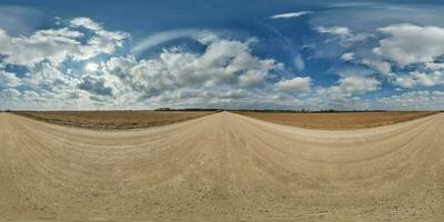 spherical 360 hdri panorama on gravel road with clouds and sun on blue sky in equirectangular seamless projection, use as sky replacement in drone panoramas, game development as sky dome or VR content photo